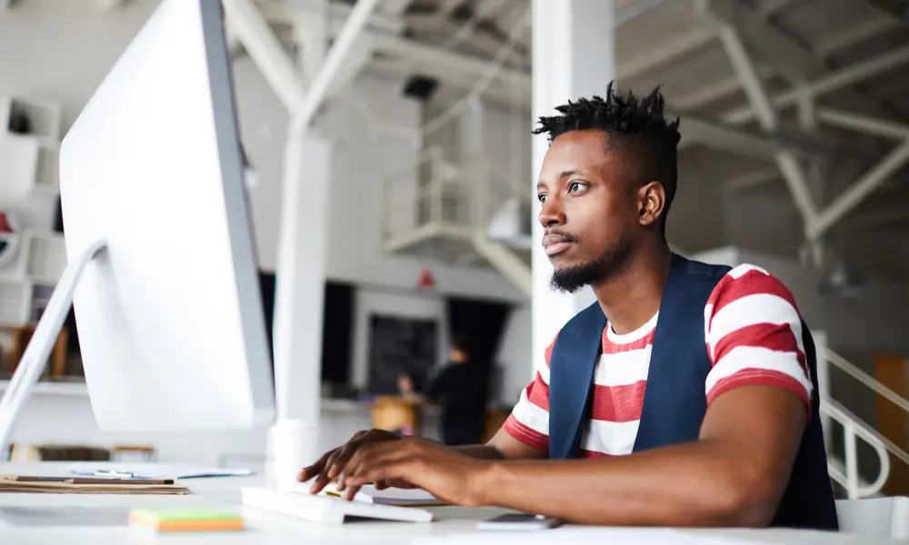 Web Development Black man working on a desktop computer.